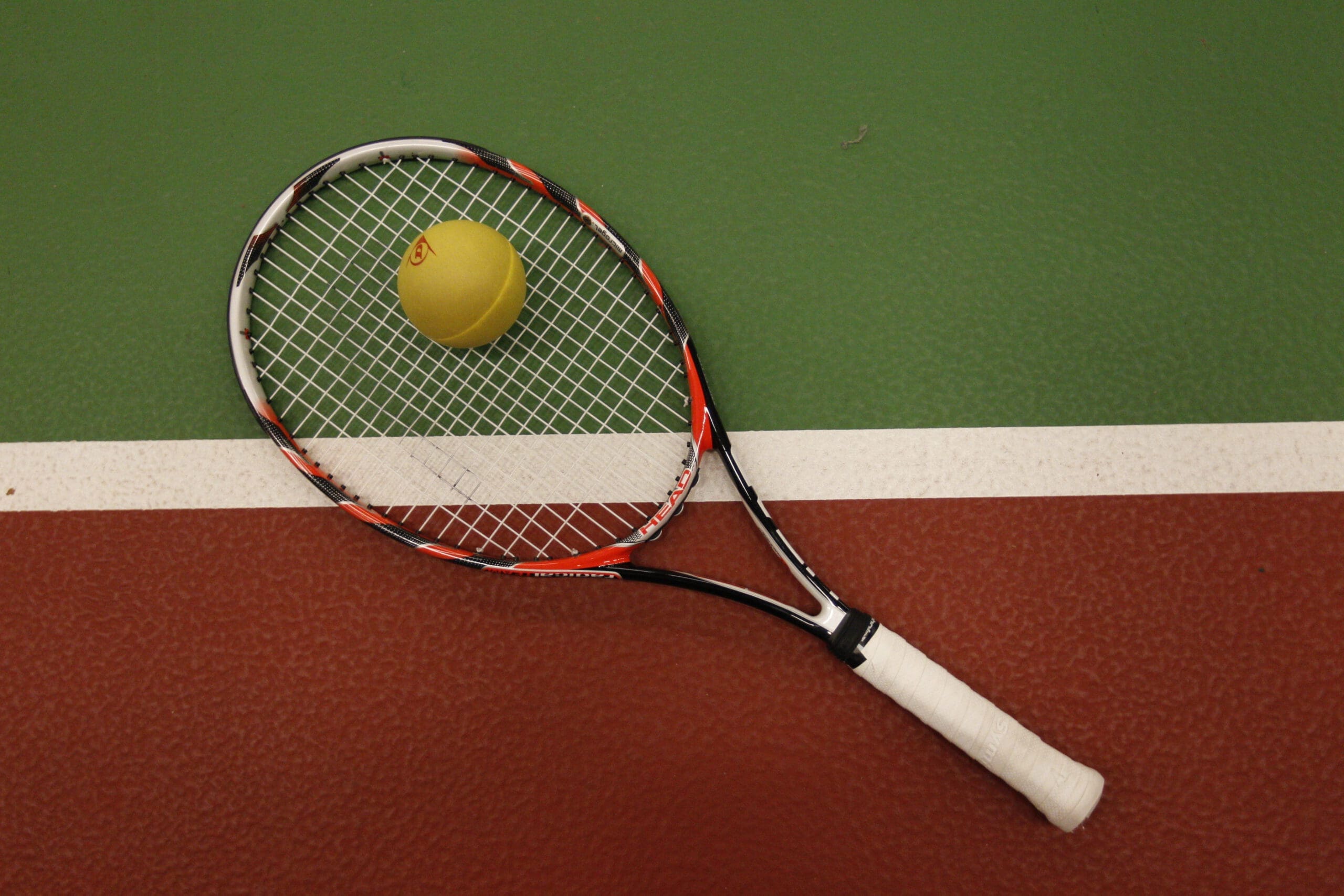 Tennisracket met bal op lijnen van een tennisveld