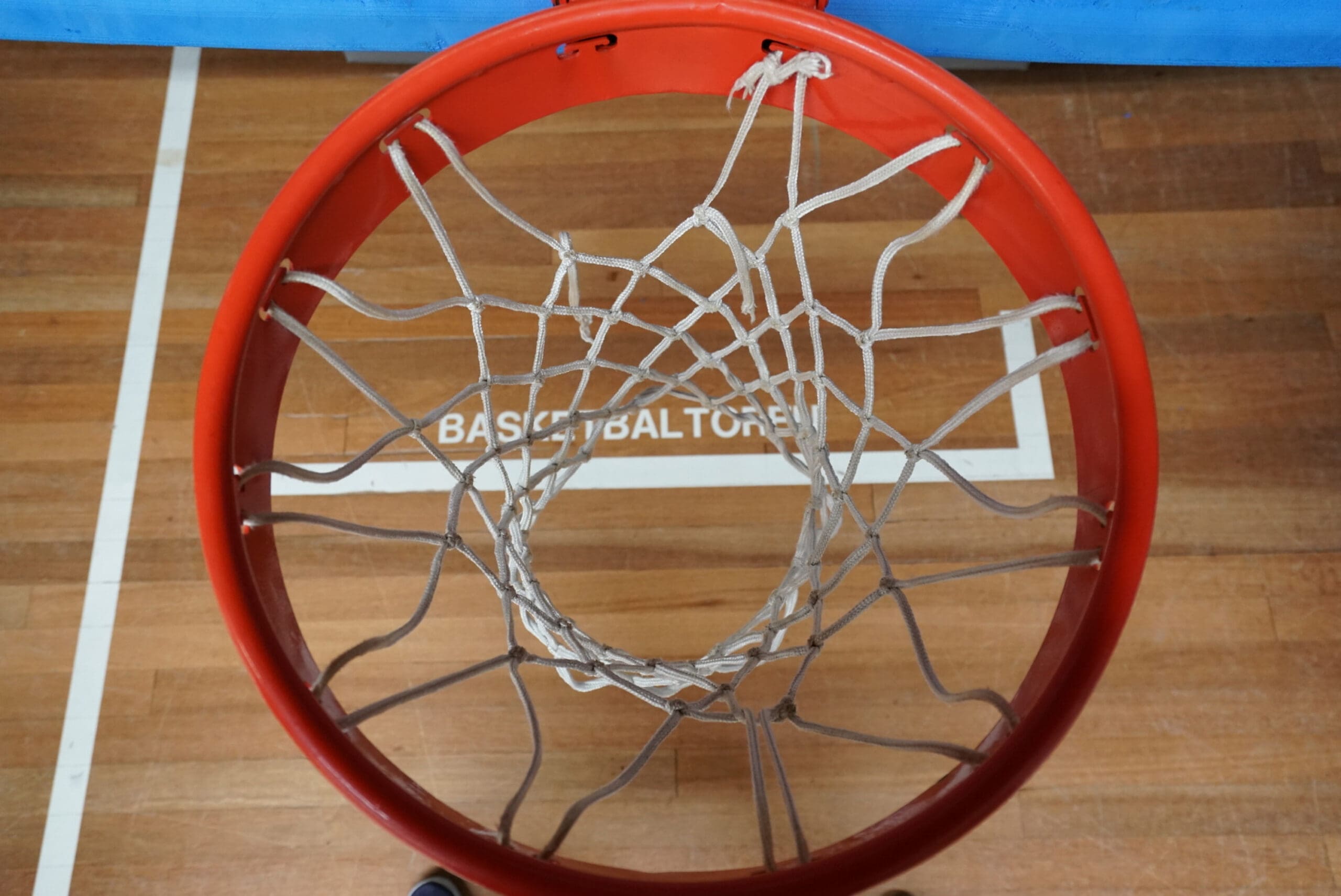 Doorkijkje van bovenaf door basket richting houten sportvloer