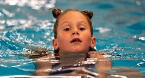 zwemmend meisje met twee knotjes in het haar