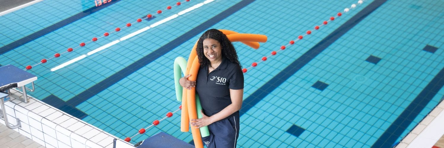 Collega met Pool noodles in haar arm kijkt lachend de camera in