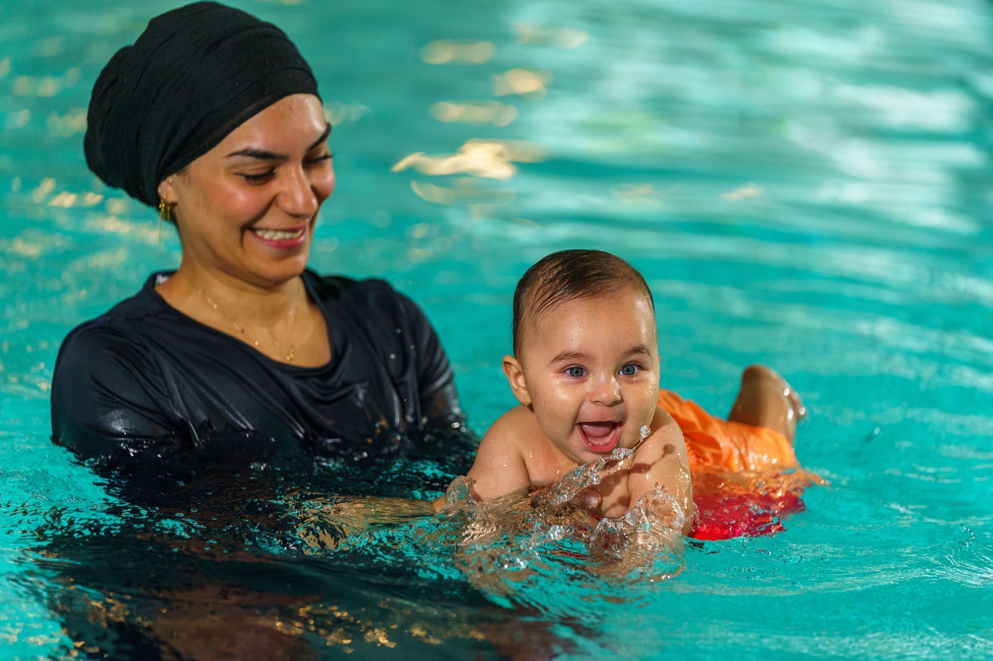 vrouw in burkini zwemmen met zoon